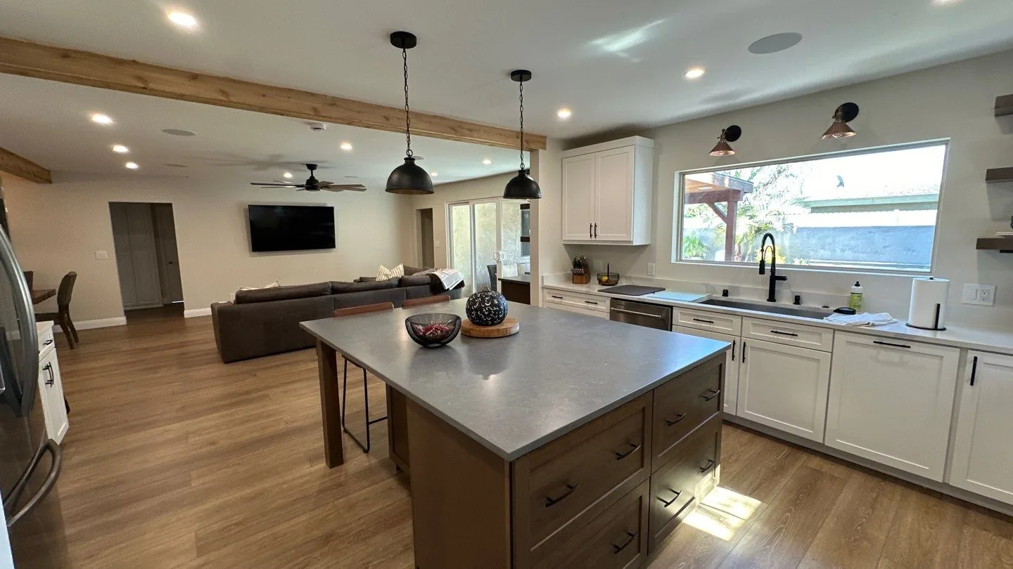 Open concept South Bay kitchen remodel with a gray quartz island, white cabinetry, and an exposed wood ceiling beam
